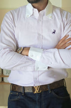 Man wearing a striped dress shirt with a logo, arms crossed, on a neutral background