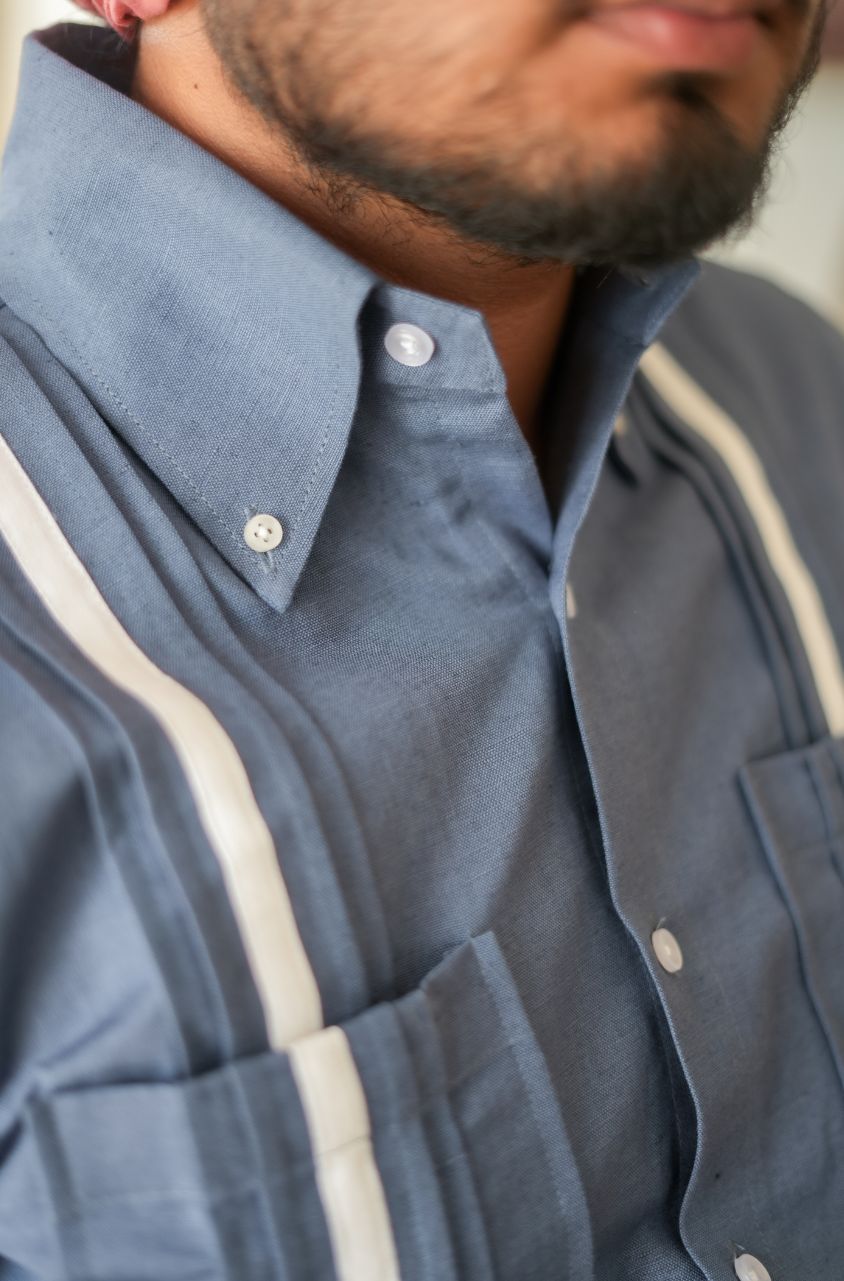 Close-up of a person wearing a blue shirt with white stripes on the chest.