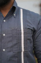 Close-up of a person wearing a dark blue shirt with a white stripe.