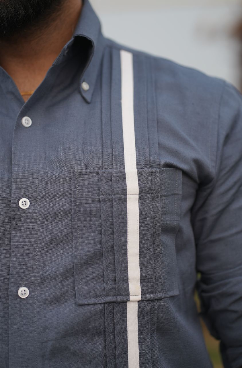 Close-up of a person wearing a dark blue shirt with a white stripe.