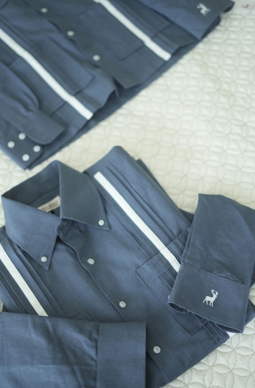 Folded navy blue shirts with white stripes on a textured surface by luxento