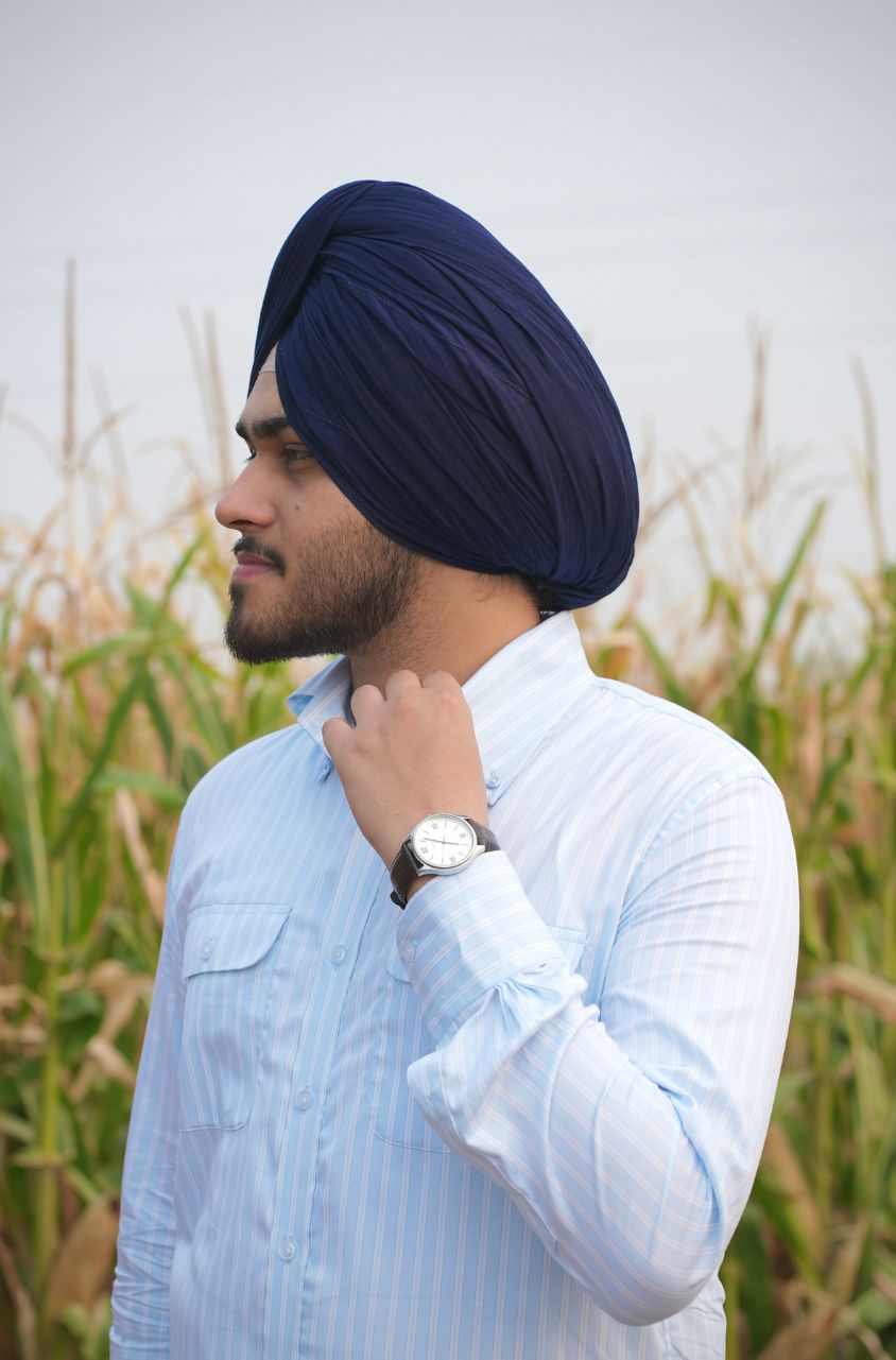 Man wearing a navy blue turban and light blue shirt in a field
