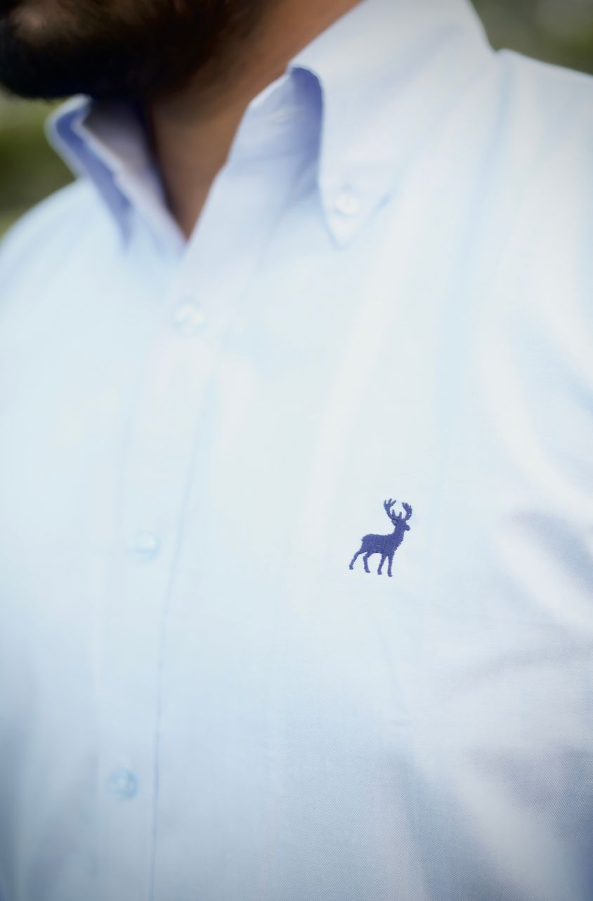 Light blue shirt with a small logo on a blurred background