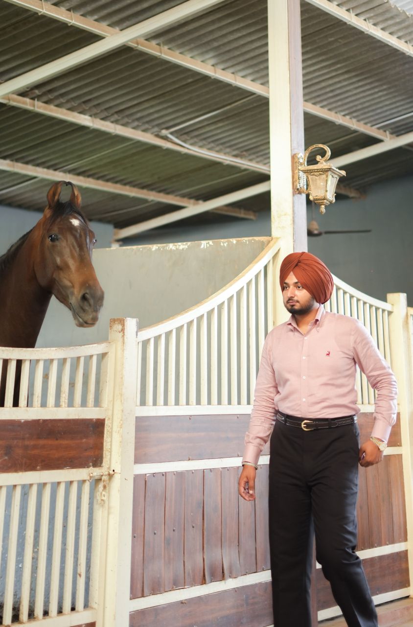 Man walking next to a horse in a stable