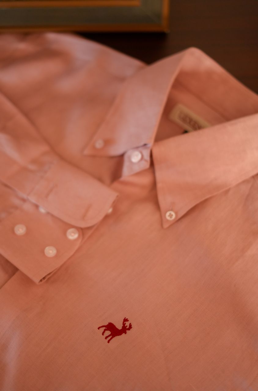 Close-up of a pink shirt with a small logo on a blurred background by luxento
