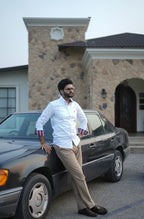 Man leaning against a car in front of a stone building