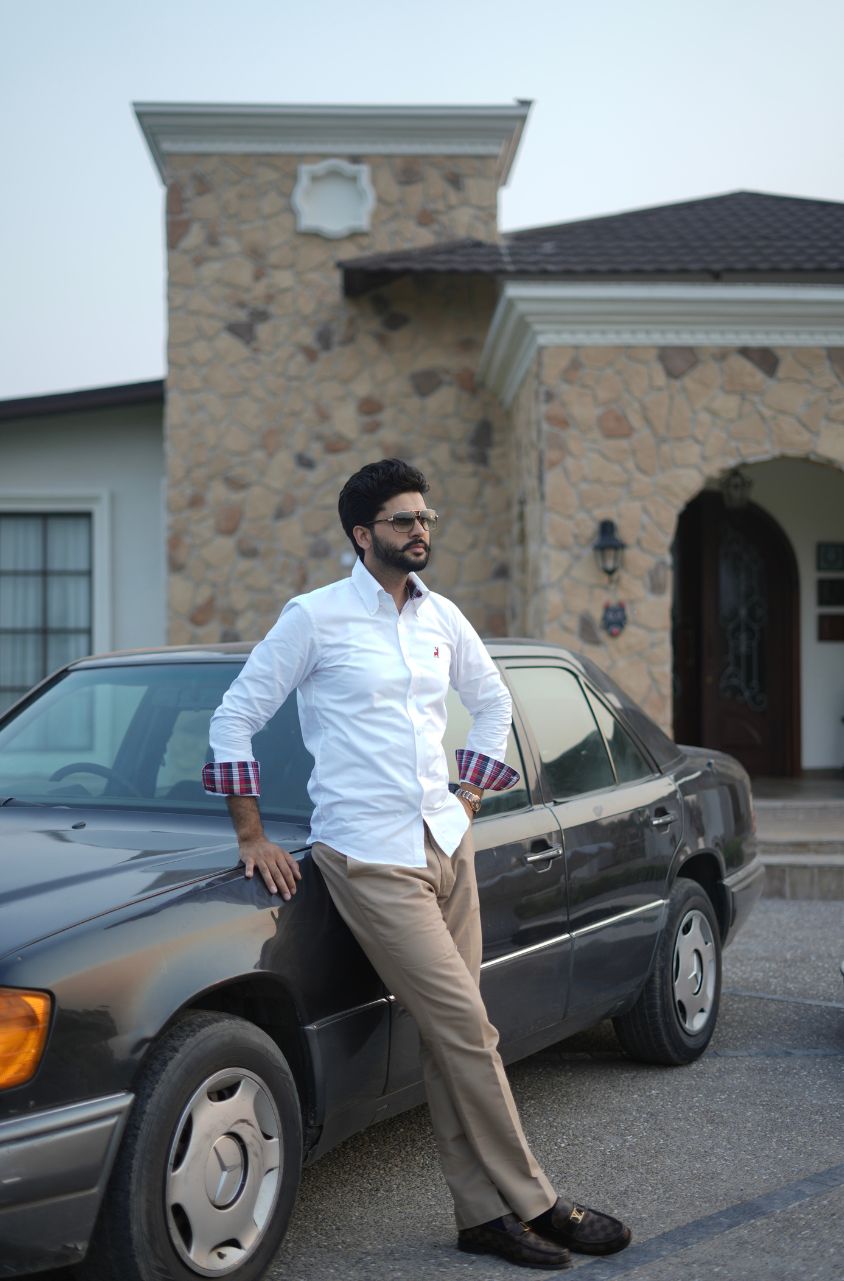 Man leaning against a car in front of a stone building