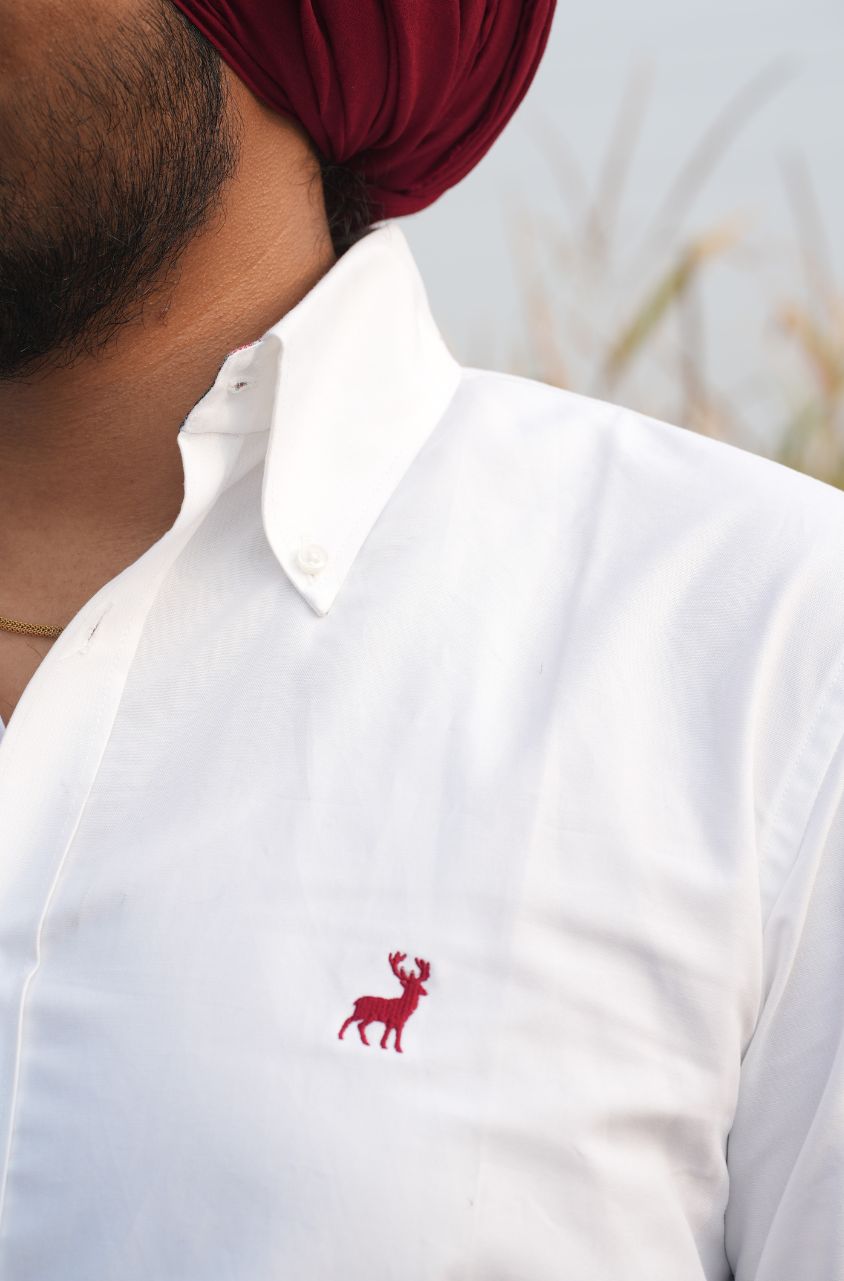 White shirt with a red deer logo worn by a person with a red turban.