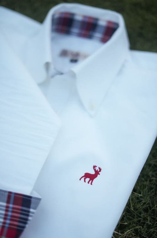 White dress shirt with plaid cuffs and red deer emblem on a grassy background